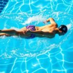 Gyerek úszik a medencében, erősítve az állóképességét és formálva a testét.